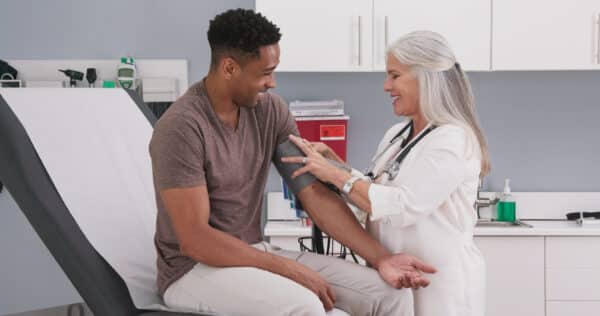 Mature white female physician checking male patients blood pressure at clinic Customer service bright ideas medical consulting
